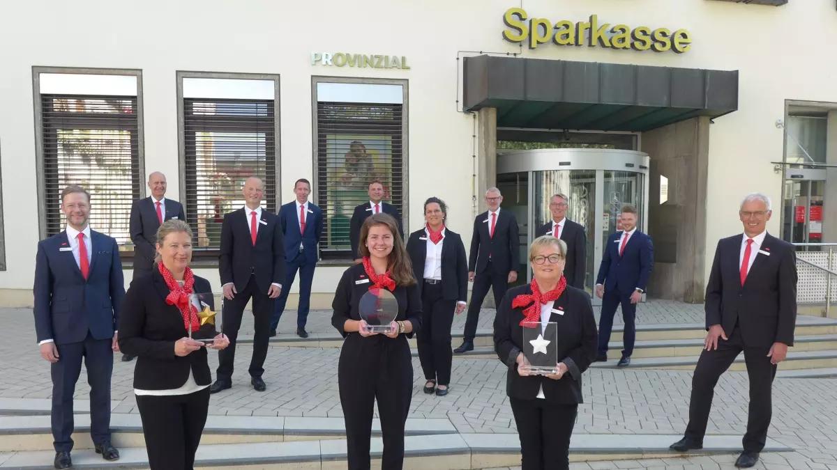 Das Foto zeigt Heinz-Jörg Reichmann (links) und Bernd Schablowski (rechts) sowie die Mitarbeiter der Sparkasse mit den Auszeichnungen.