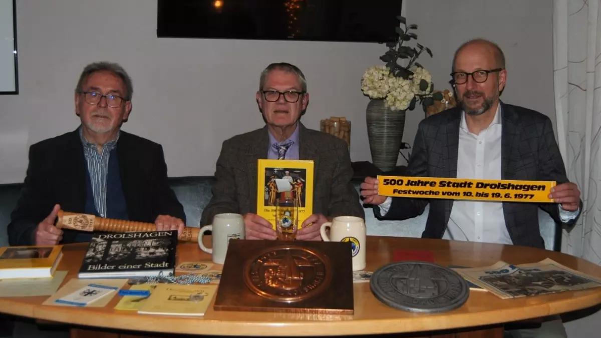Dr. Peter Vitt, Leiter der Geschichtswerkstatt, Heinz Joachim Sack, Autor des Buches, und Bürgermeister Uli Berghof (von links) präsentieren das neue Buch und zahlreiche Utensilien aus dem Jubiläumsjahr.