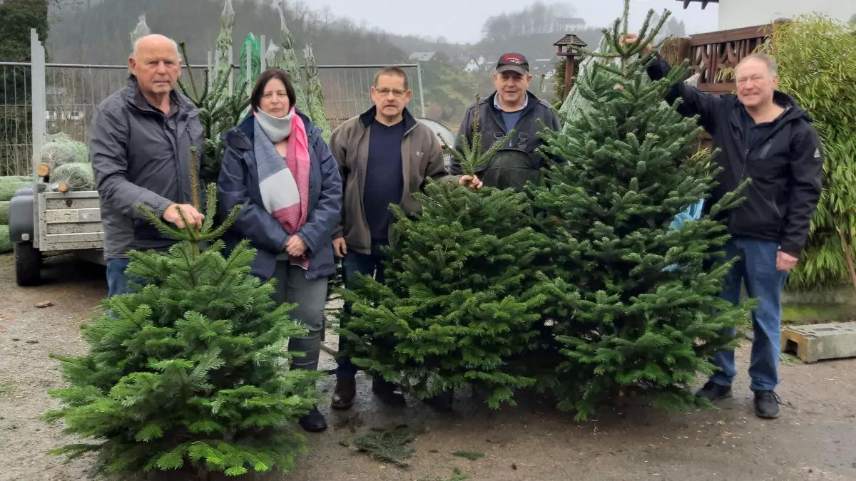 Rainer Krahl (3.v.l.) und Lothar Schenk (2.v.r.) übergeben die Weihnachtsbäume an Josef Buchal l.), Elke Knappe und Jürgen Steinberg.