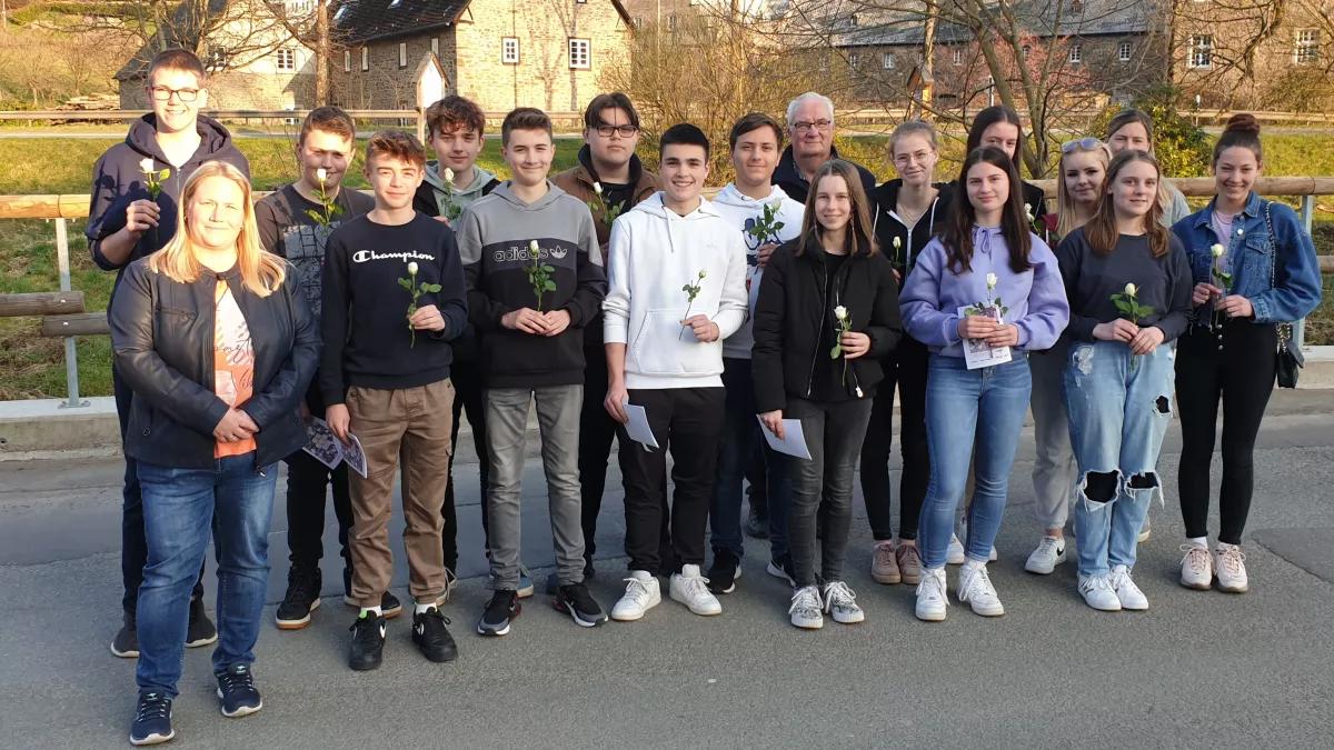 Die Lenhauser Firmgruppe mit den Katechetinnen Nadine Rohrmann (v.l.) und Stefanie Zepke (h.r.) sowie Ortsheimatpfleger Matthias Baumeister (h.  5. von r.) vor der Niederlegung der Rosen an den Stolpersteinen.