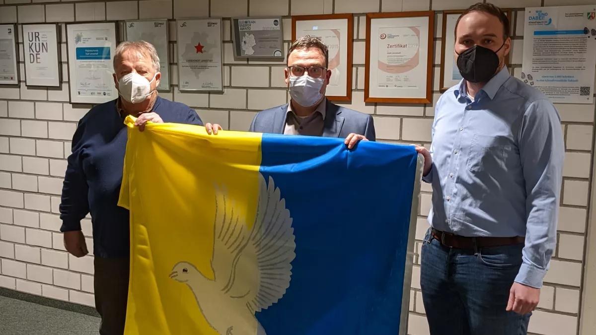 Heinz Vollmer (l.) und Sebastian Sonntag (r.) überreichten die Friedensfahne an den Beigeordneten Karsten Schürheck.