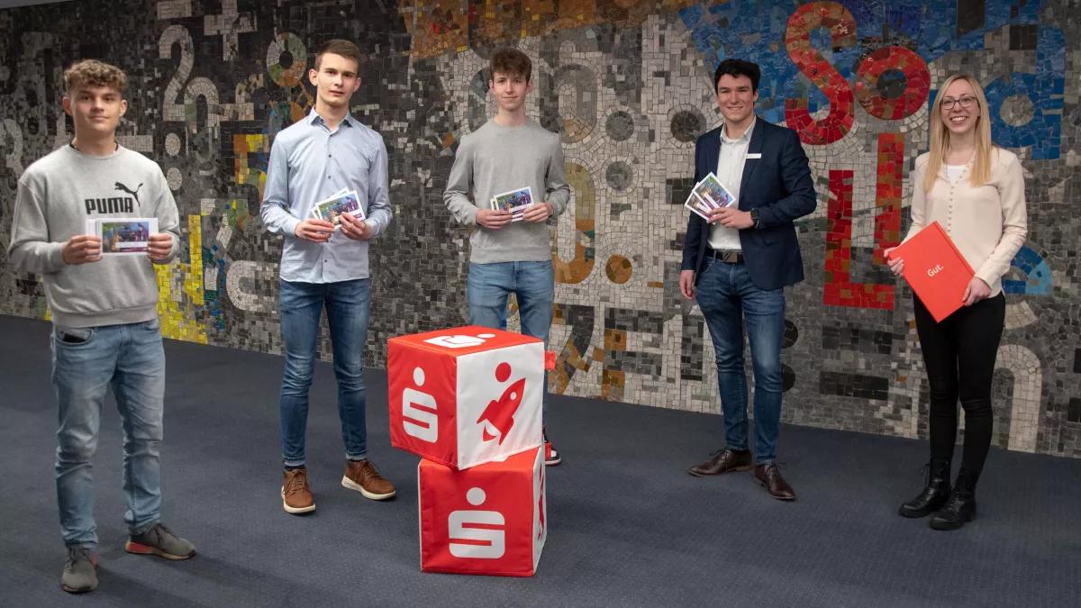 Von links: Max Ruch (erster Platz), Johannes Arens (zweiter Platz), Kilian Kinkel (dritter Platz) und Pius Philipps (Sparkassen-Azubi-Team) erhielten von Marketing-Mitarbeiterin Nina Graeve die „Olper Mark-Gutscheine“ als Anerkennung für ihre Leistungen in den Börsen-Teams.