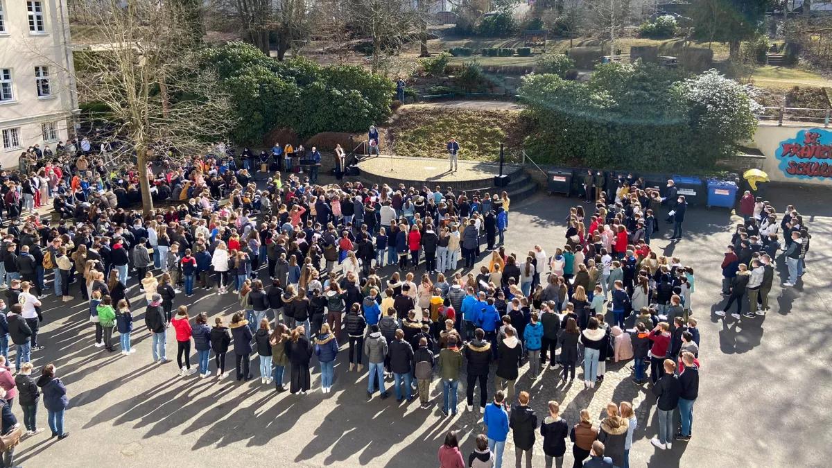 Die Schulgemeinde versammelte sich auf dem Schulhof, um gemeinsam für Frieden zu beten, zu singen und die schuleigene Friedensfahne zu segnen.