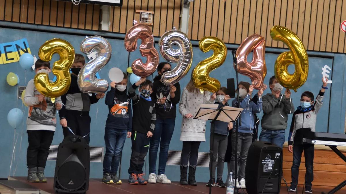 Mit Freude und berechtigtem Stolz zeigen die Schüler die Spendensumme von 32.392,46 Euro mit Ballons.