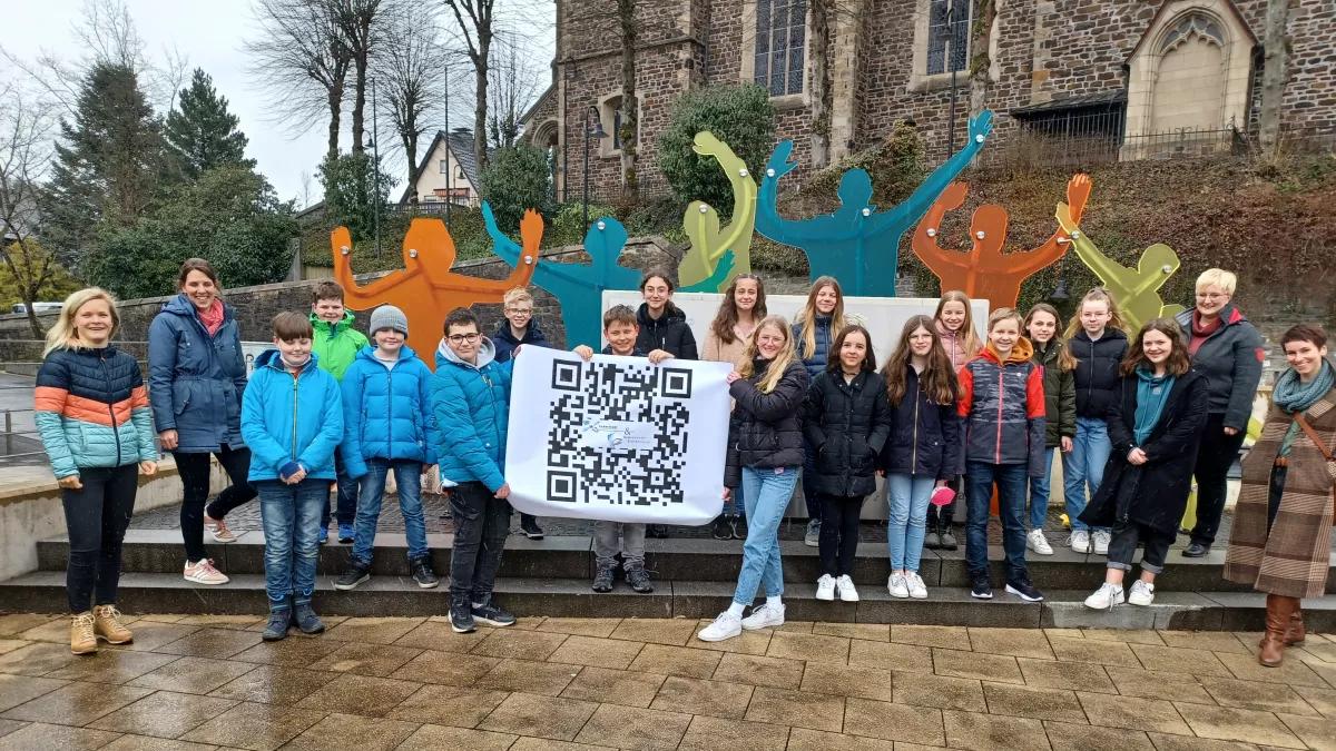 Auf dem Marktplatz wird demnächst ein QR-Code interessante Informationen liefern: Schüler des GymSLs freuen sich gemeinsam mit Luisa Möser, Silke (ganz links) sowie mit Kathrin Schröder und Antonia Krihl (ganz rechts) auf dem Start des gemeinsamen Projektes.